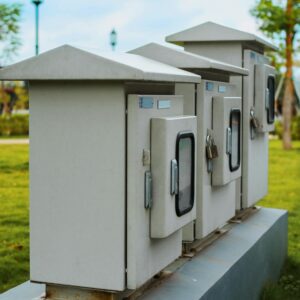 Close-up of locked electric boxes outdoors, featuring metal cabinets on a platform.